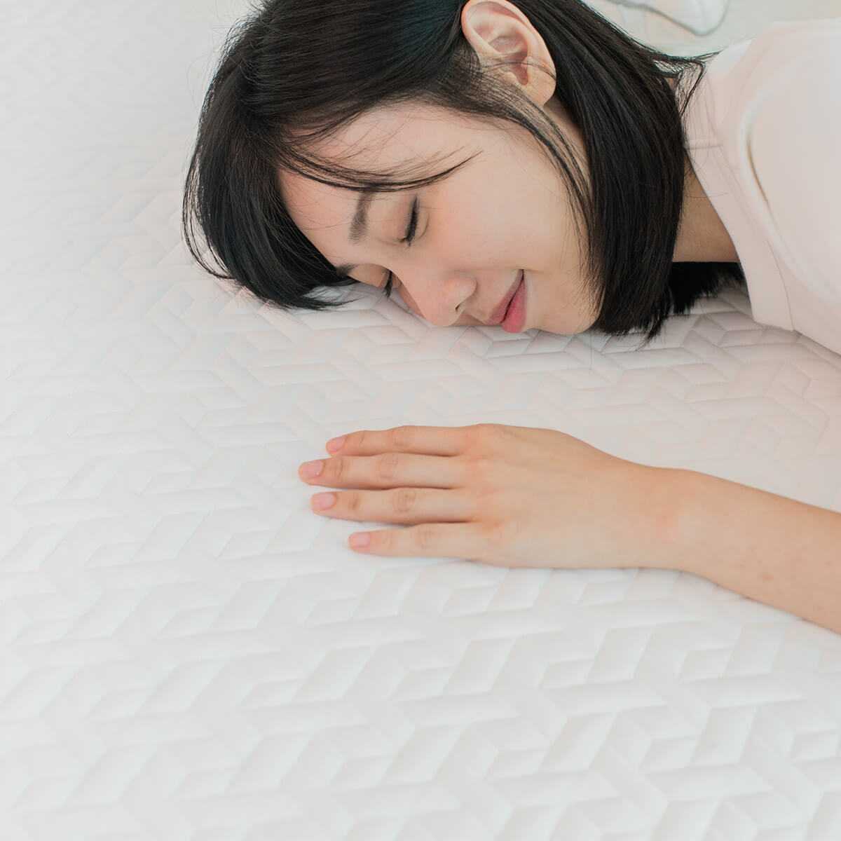 Girl lying face down on an Amazeam mattress, hand feeling the texture of the cover, highlighting the mattress's comfort and cooling.