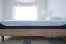 Load image into Gallery viewer, Side view of the Amazeam mattress on a Scandinavian-style IKEA bed frame, featuring a cool-touch quilted cover and a minimalist design, in a bright room with a white fluffy rug on the floor